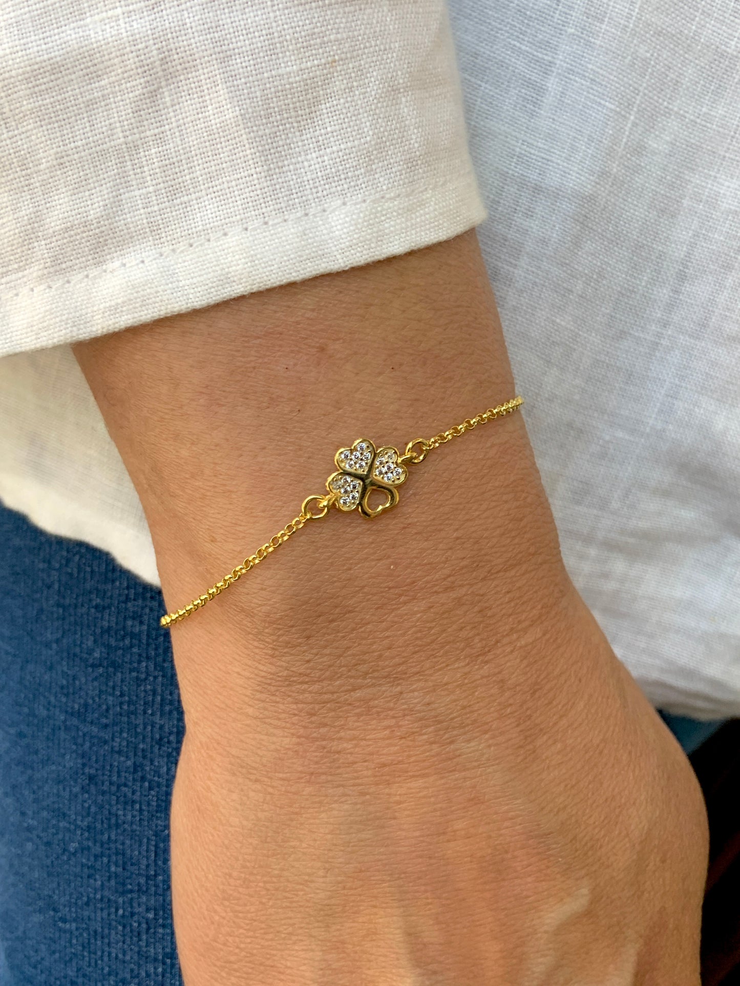 Gold clover leaf bracelet worn on wrist